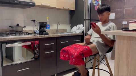 Um menino está sentado na cozinha se masturbando